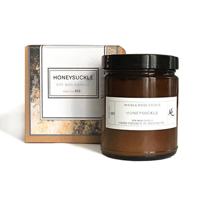 Delicate honeysuckle-scented soy wax candle in a sleek gold travel tin, emitting a sweet, floral aroma.